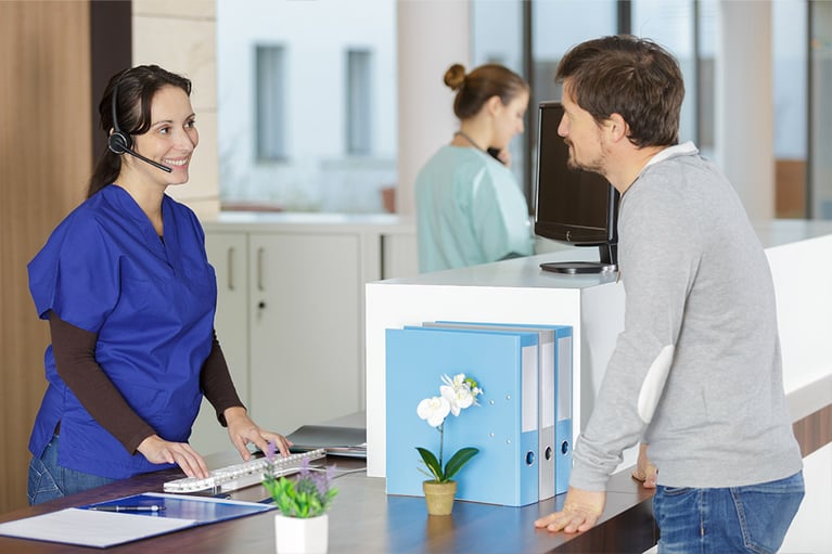 patient looking at female receptionist using headset phone at reception