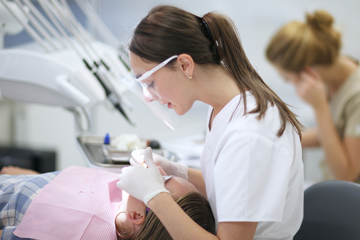 A dental student cleaning a patients teeth in a dental clinic