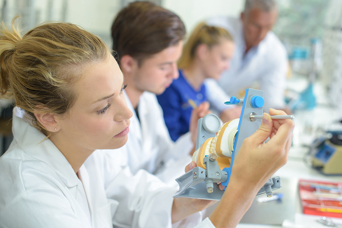 students working on false teeth in a classroom