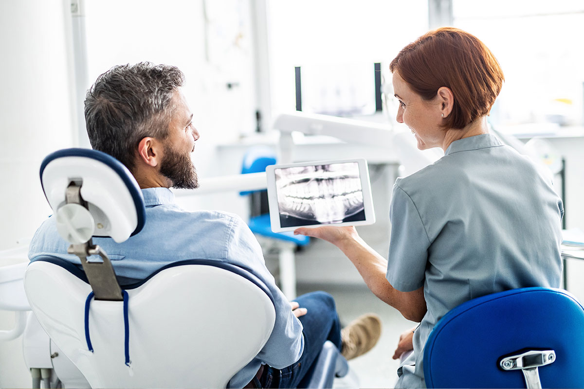 dentist and patient looking at xray of teeth