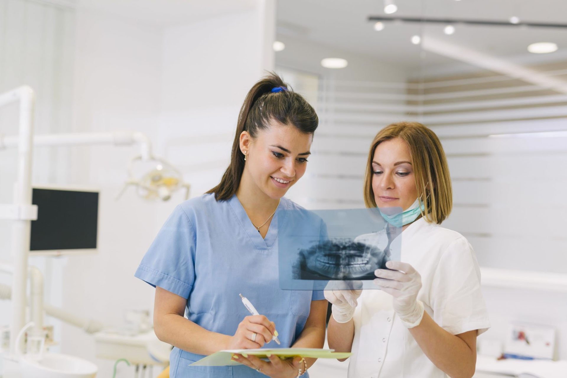 woman dentist with her assistant examine dental x-ray