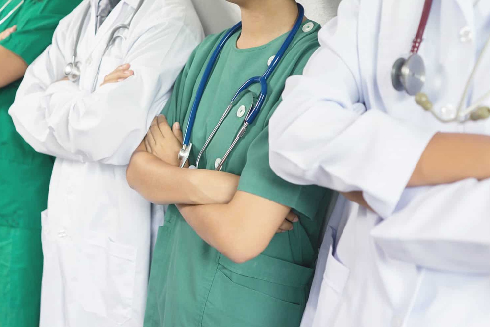 group of four dentists standing in a row with their arms crossed