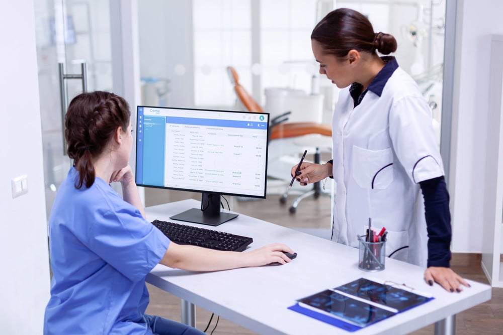 dentist speaking with nurse at her desk in the front office